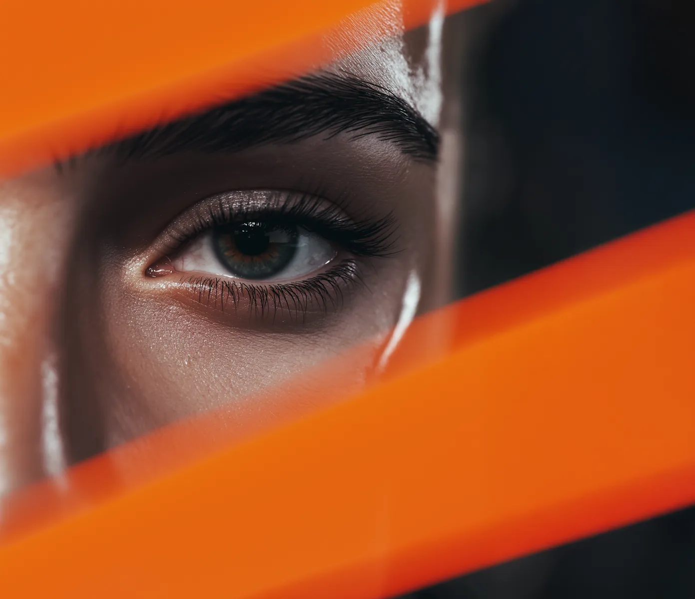 Close-up of an eye partially covered by orange fabric — representing fragmented identity